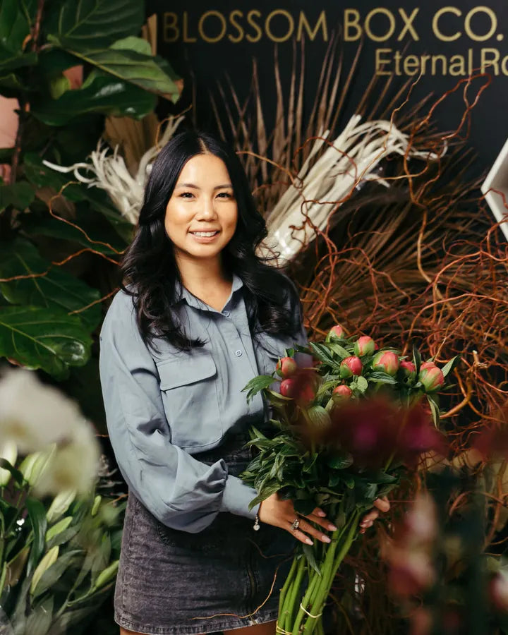 Trinh, founder of Blossom Box Co., holding fresh blooms in the Prospect studio