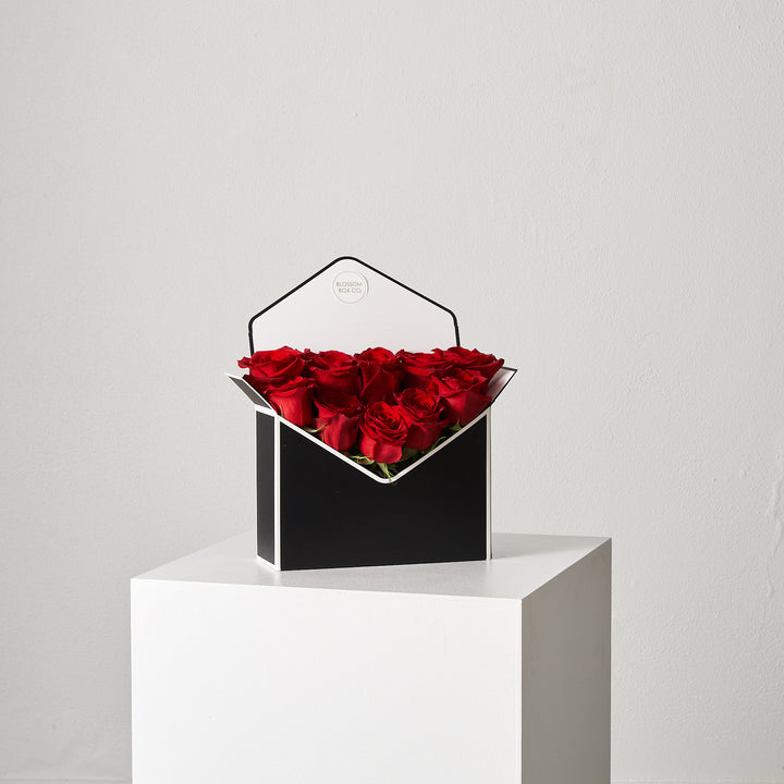 Love Letter Box in black filled with red Ecuadorian roses on a white plinth