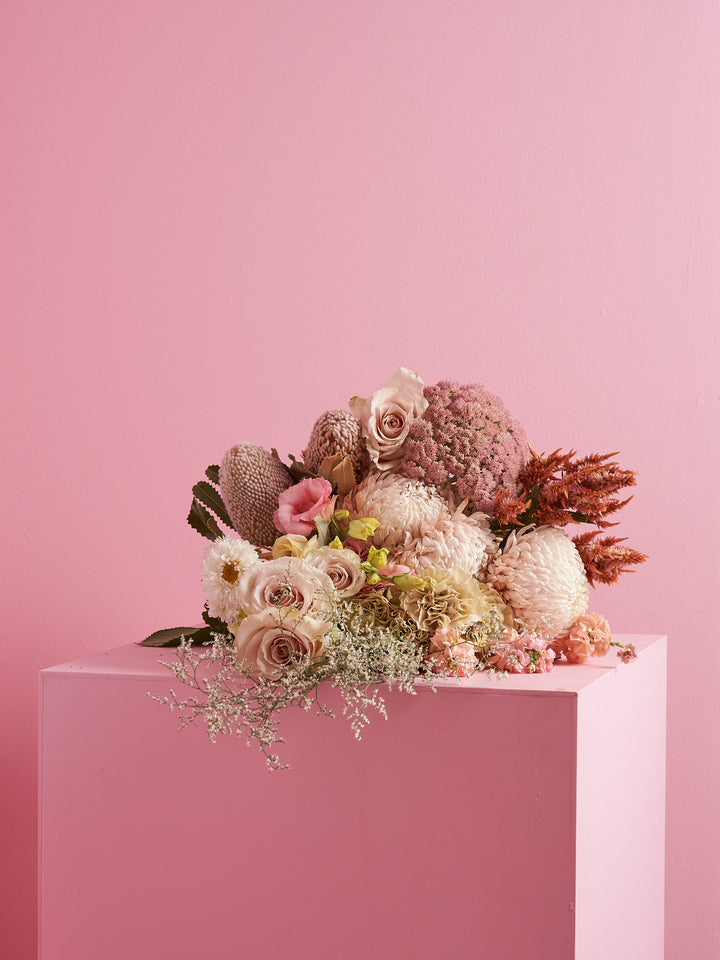 Flower subscription bunch of pink and cream roses and seasonal flowers on a pink plinth