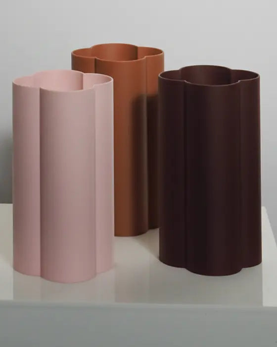 Fluted Emblem Vessels in blush, terracotta and chocolate on a white plinth